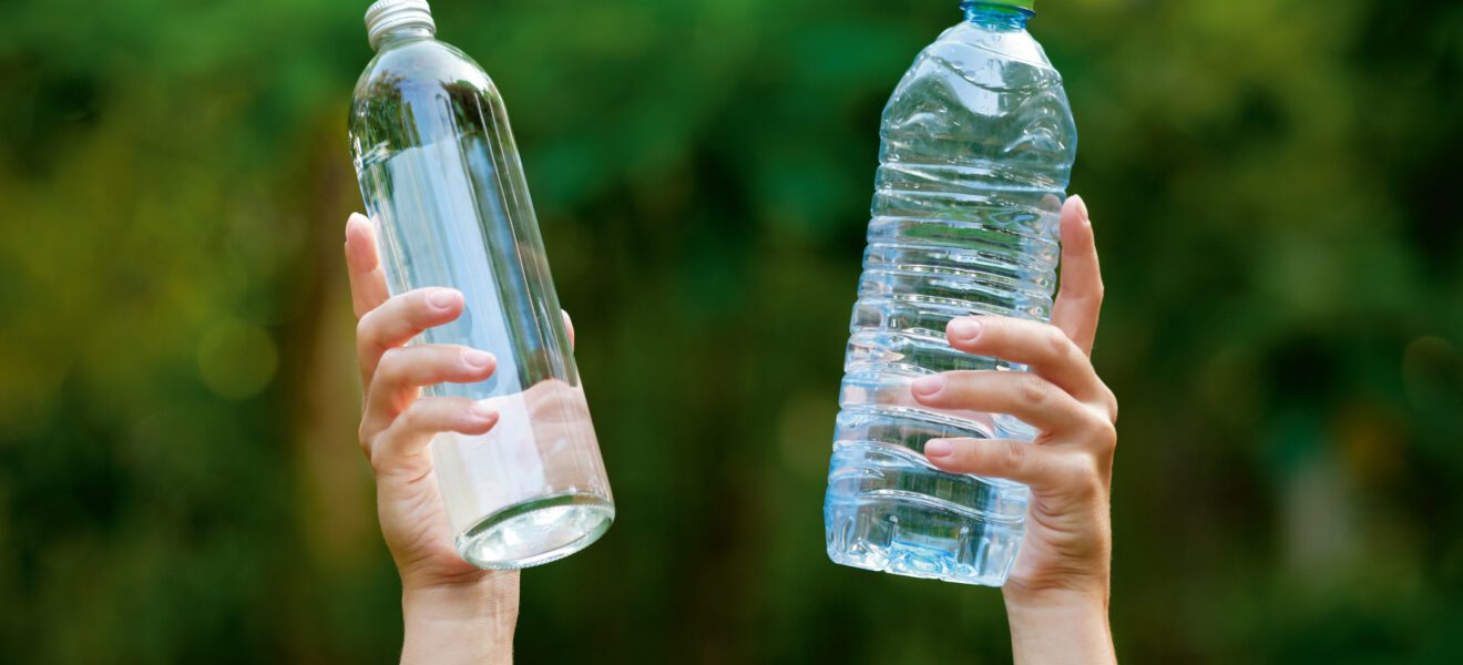 Zwei Hände halten eine Einwegflasche und eine Mehrwegflasche