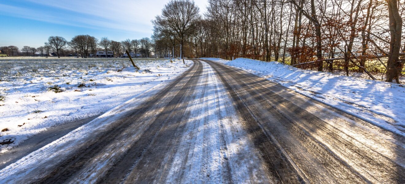 glatte leere Straße im Winter überfroren mit Eis und Schnee