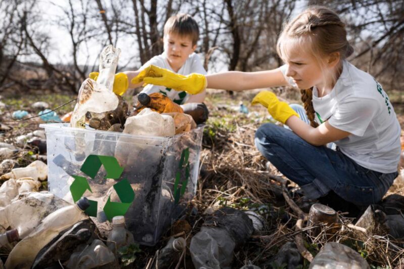 Kinder sammeln Plastikmüll im Wald zur Wiederverwertung und Umweltschutzaktion