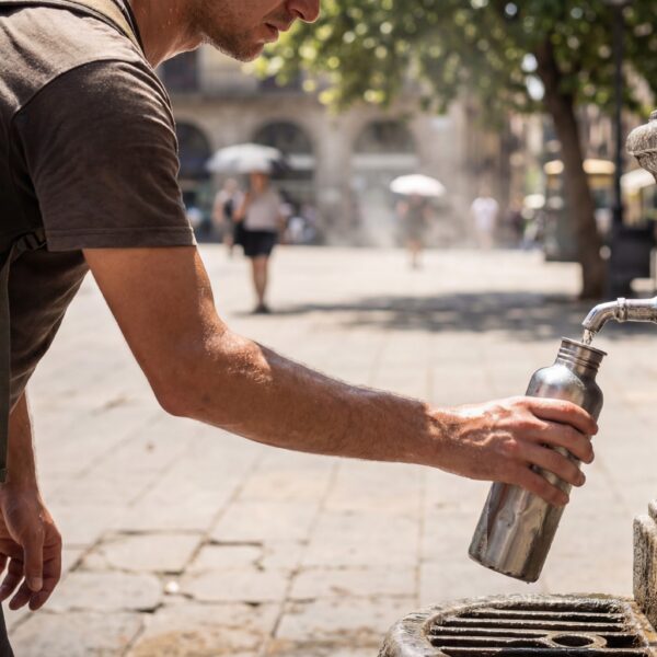 Mann füllt Wasserflasche an Trinkbrunnen in der Stadt auf.